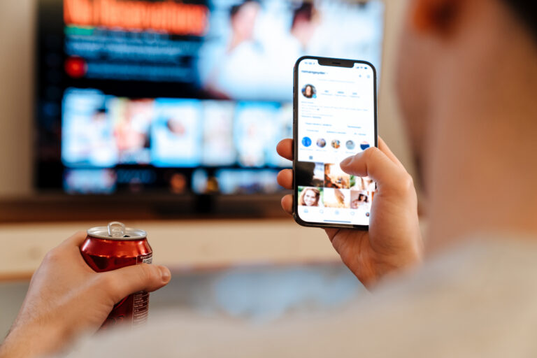 Phone with Instagram app open in front a blurred tv
